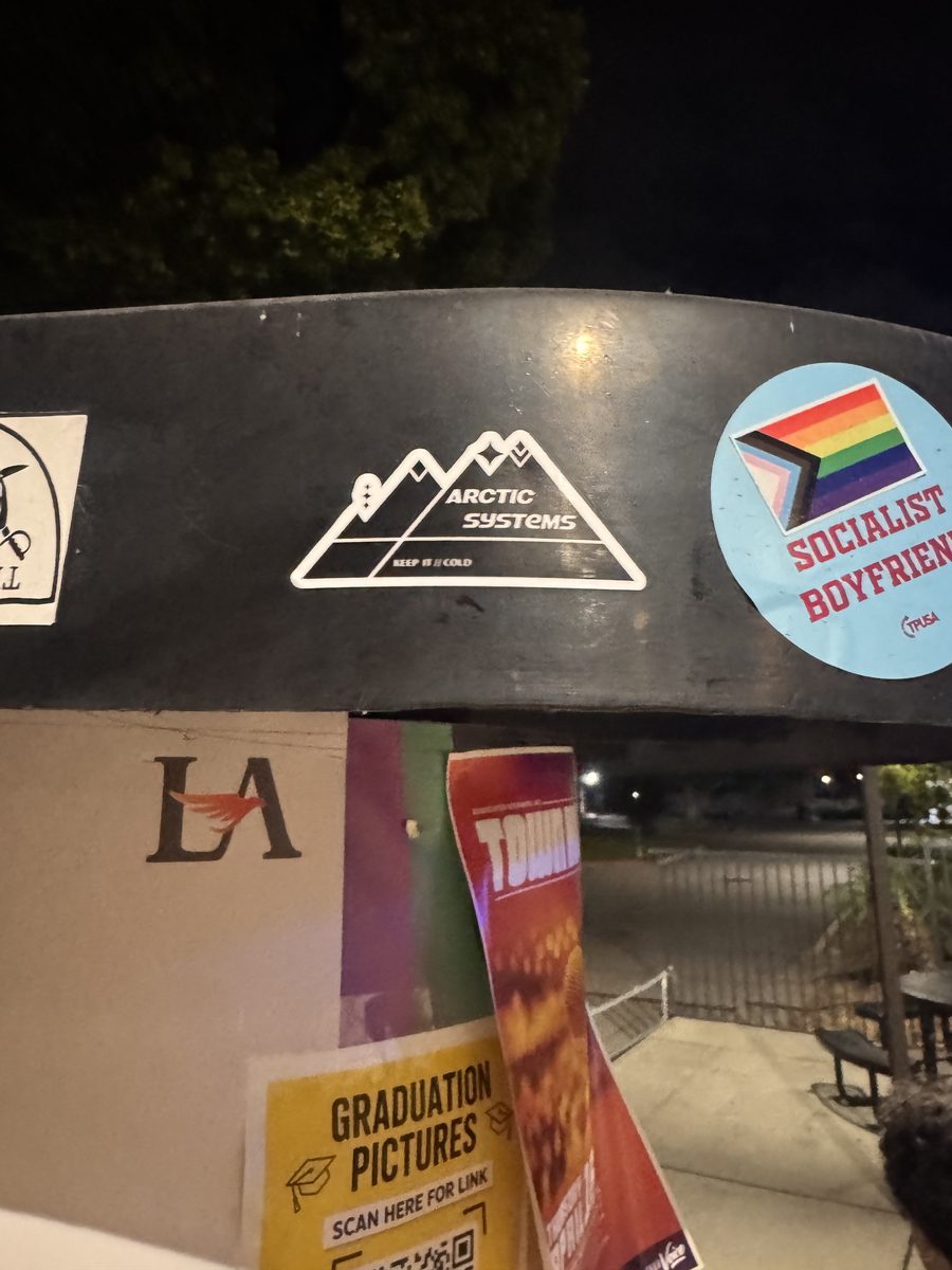 An Arctic Systems sticker on a metal sign covered with stickers and flyers at night